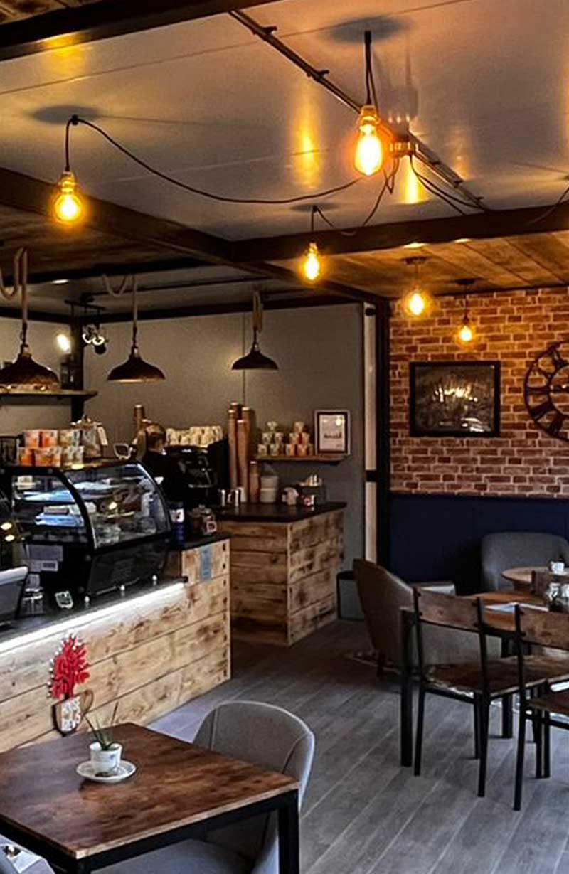 House of Brews coffee shop with a wooden counter, red brick walls, grey floor and industrial hanging lights.